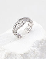 Silver open ring with textured design on a white background