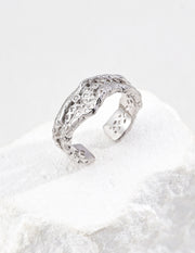 Silver open ring with textured design on a white background